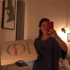 a woman taking a selfie while holding a pizza box