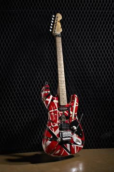 a red and white guitar sitting on top of a table