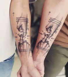 two people holding hands with tattoos on their arms