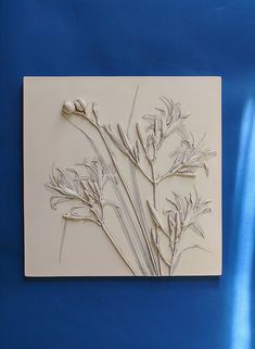 a white tile with flowers on it against a blue background and a light blue wall