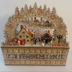 a christmas scene with houses and trees in the snow on a wooden box ornament