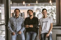 three men sitting next to each other in front of a window with the words creative on it