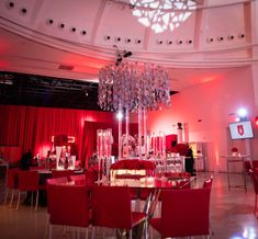 a room filled with lots of red chairs and tables covered in crystal chandelier