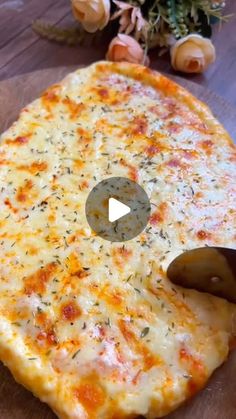 a cheese pizza is cut into pieces on a cutting board with flowers in the background