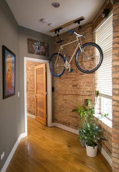 there is a bike hanging from the ceiling in this room with wood flooring and brick walls