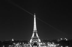 the eiffel tower lit up at night in black and white, as seen from across the river