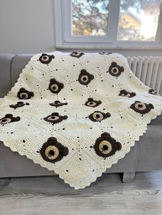 a crocheted blanket on a couch in front of a window with an owl design