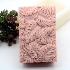 a close up of a soap block on a table next to some flowers and a plant