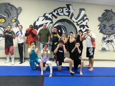 a group of people standing on top of a blue mat in front of a wall