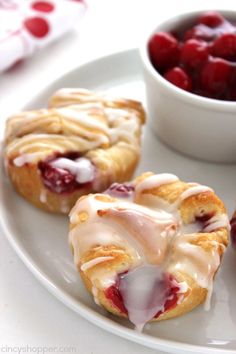 a white plate topped with pastries next to a bowl of cherries