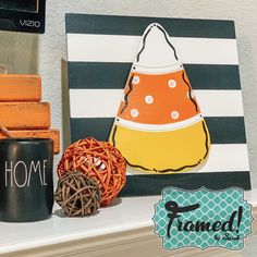 an orange and white pumpkin sitting on top of a shelf next to a black mug