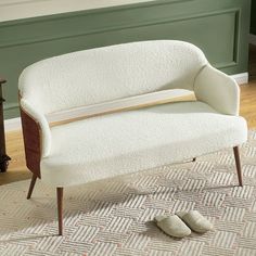 a white couch sitting on top of a rug next to a wooden table and chair