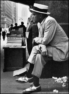 a man sitting on a bench next to a pile of books