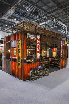 a motorcycle is parked in front of a small container on display at an exhibition or show