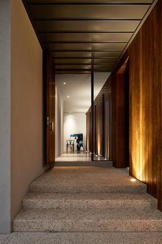 the hallway is lined with wooden doors and steps that lead up to an open floor plan