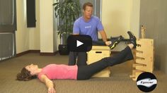 a woman laying on the floor while another man works on an exercise bike in front of her