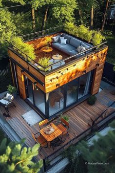 an aerial view of a small house in the woods with decking and patio furniture