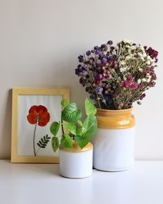 two vases with flowers in them sitting on a table next to a framed photo