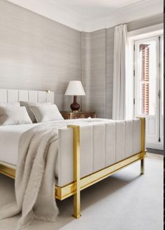 a white bed with gold frame in a bedroom