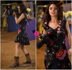 a woman in a black dress is holding a camera and wearing cowboy boots with her right hand on her hip