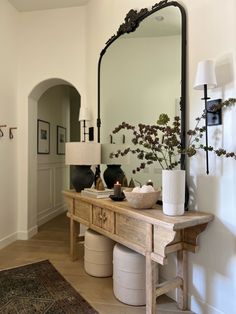 a large mirror sitting on top of a wooden table next to a vase filled with flowers