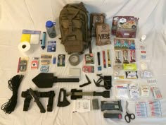 the contents of a backpack laid out on a white sheet with scissors and other items