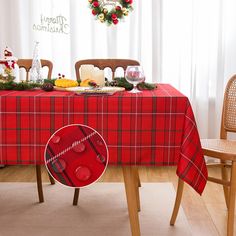 a christmas table setting with red and green plaid cloth on the table, surrounded by wooden chairs