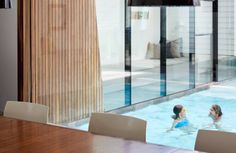 two children playing in an indoor pool next to a sliding glass door that leads out onto the patio