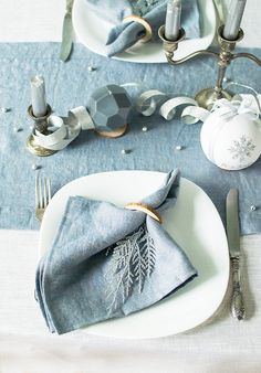 a white plate topped with a blue napkin next to a silver candelabra