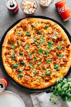 a pizza sitting on top of a pan covered in toppings next to cans of soda