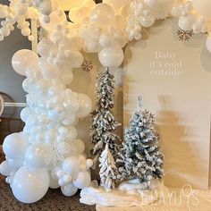 white balloons and trees are on display in front of a baby it's cold outside sign