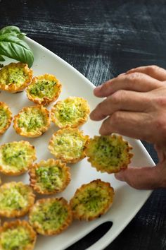 a plate with small appetizers on it and a person reaching for the one