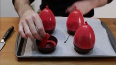 a person is decorating three red candles on a tray with a knife and fork