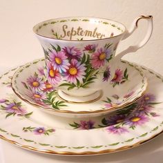 a tea cup and saucer sitting on top of each other with flowers painted on them