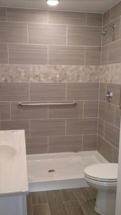 a white toilet sitting next to a bath tub in a bathroom under a ceiling light