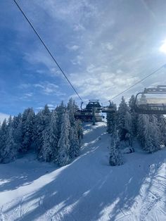 a ski lift going up the side of a snow covered mountain with trees on both sides