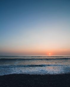 the sun is setting over the ocean with waves