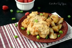 a red plate topped with potatoes and meat next to raspberries