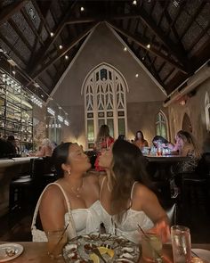 two women sitting at a table with food in front of them