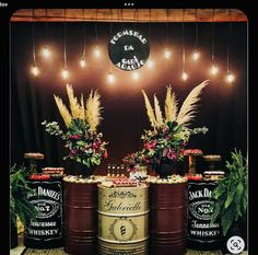 there are three barrels with flowers in them on the table next to each other and lights hanging from the ceiling