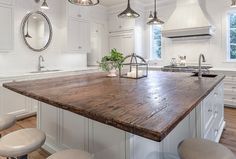 a large kitchen island with stools in front of it and lights hanging from the ceiling