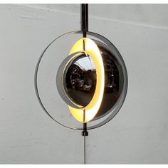 a circular light fixture hanging from the side of a wall with a mirror on it