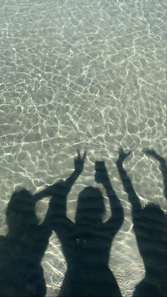 two people standing in the water with their hands up