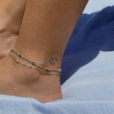 a woman's foot with a tattoo on it and a chain around the ankle