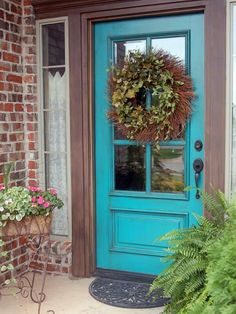 a blue front door with a wreath on it and some flowers in the potted planter