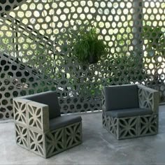 two chairs sitting next to each other in front of a pergolated wall with plants