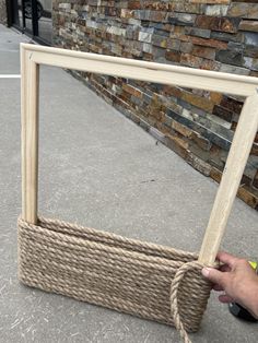 a person holding a rope in front of a large mirror on the ground next to a brick wall