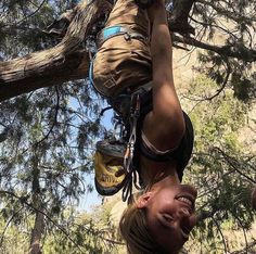 a woman hanging upside down from a tree