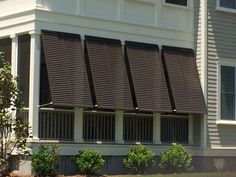 an image of a building that has some blinds on the windows and bushes in front of it