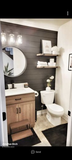 a white toilet sitting in a bathroom next to a wooden sink vanity and open door